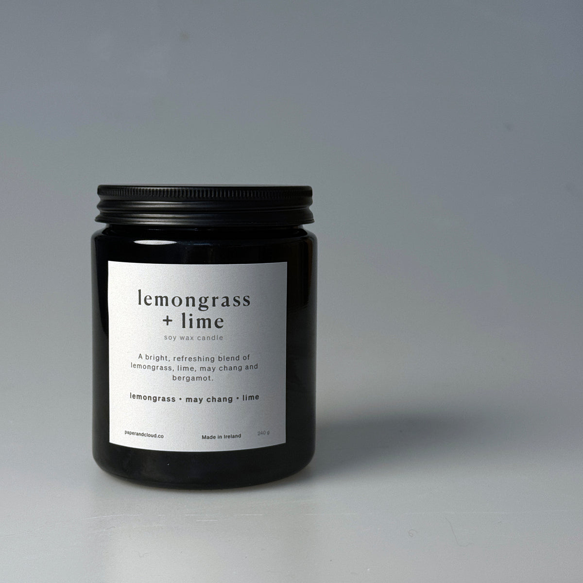Black candle jar with 'lemongrass + lime' label on a gray background